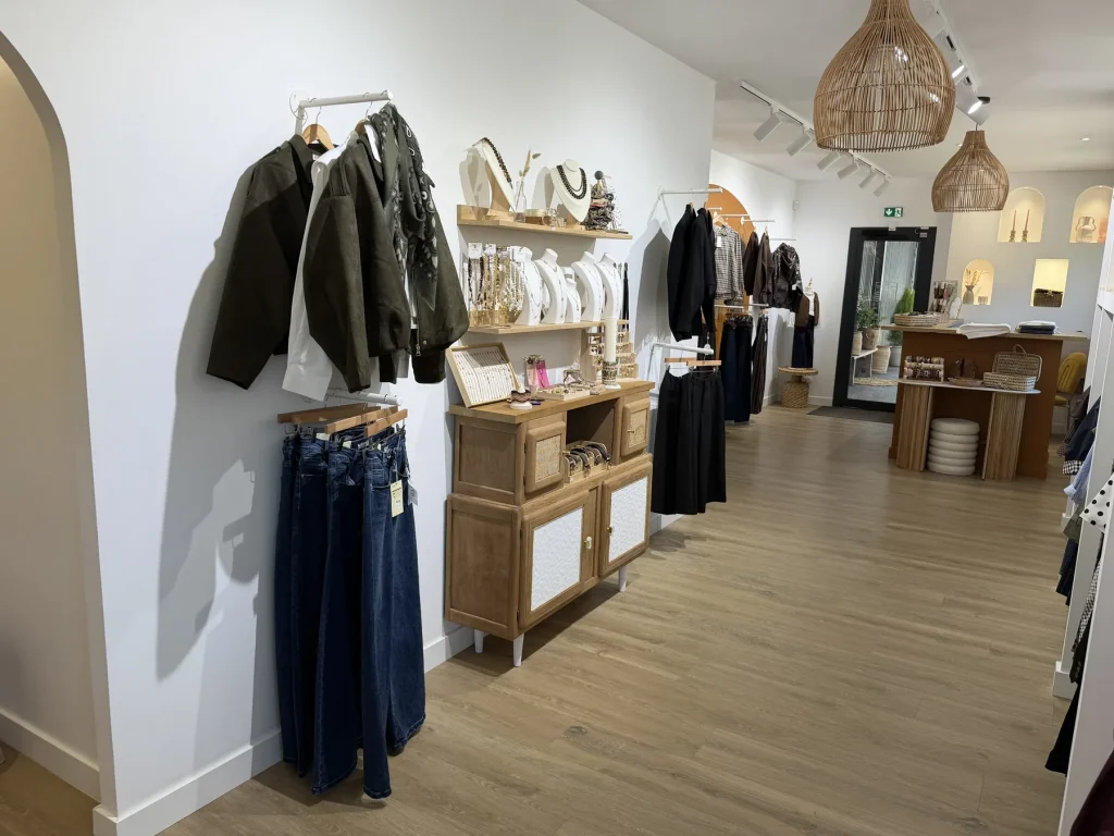 L’allée de la boutique au Houlme, veste kaki en présentation et jeans pliés sur un meuble en cannage